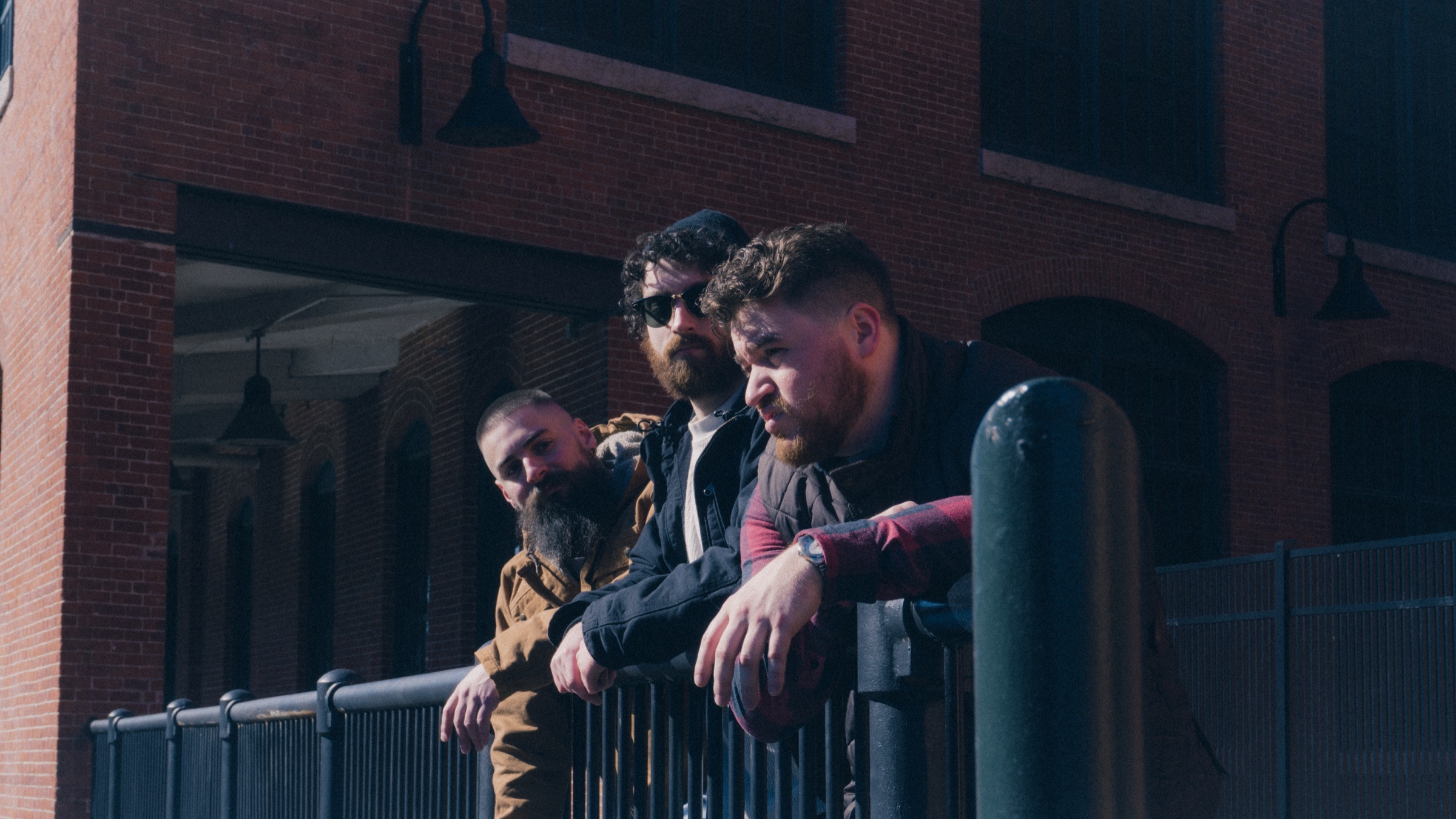 The three members of When Without together by a railing and brick building