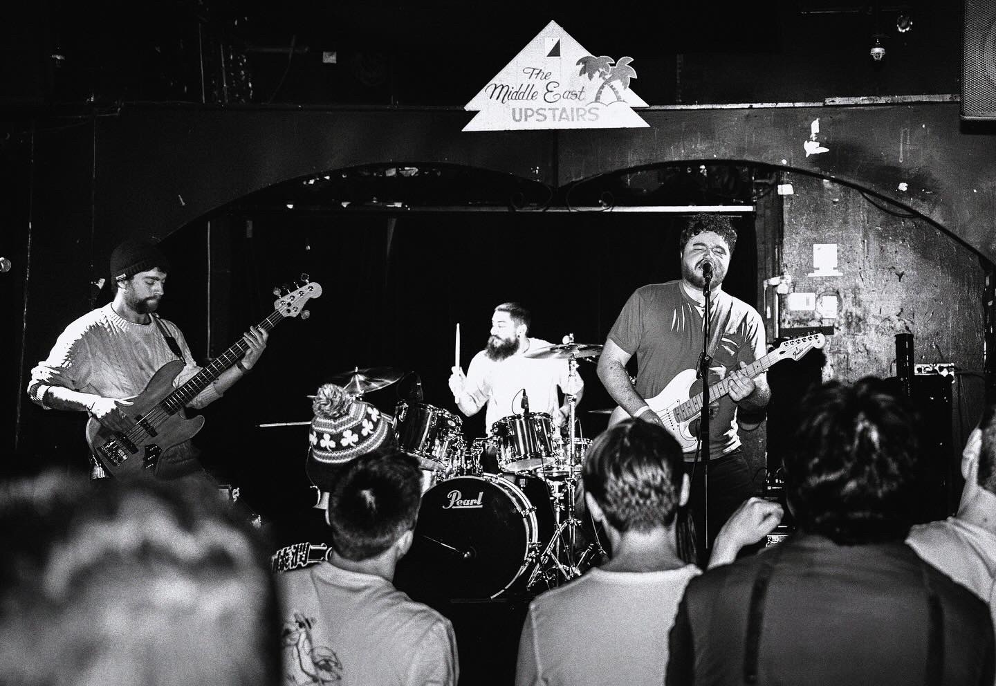 The full band performing on stage with an audience in front